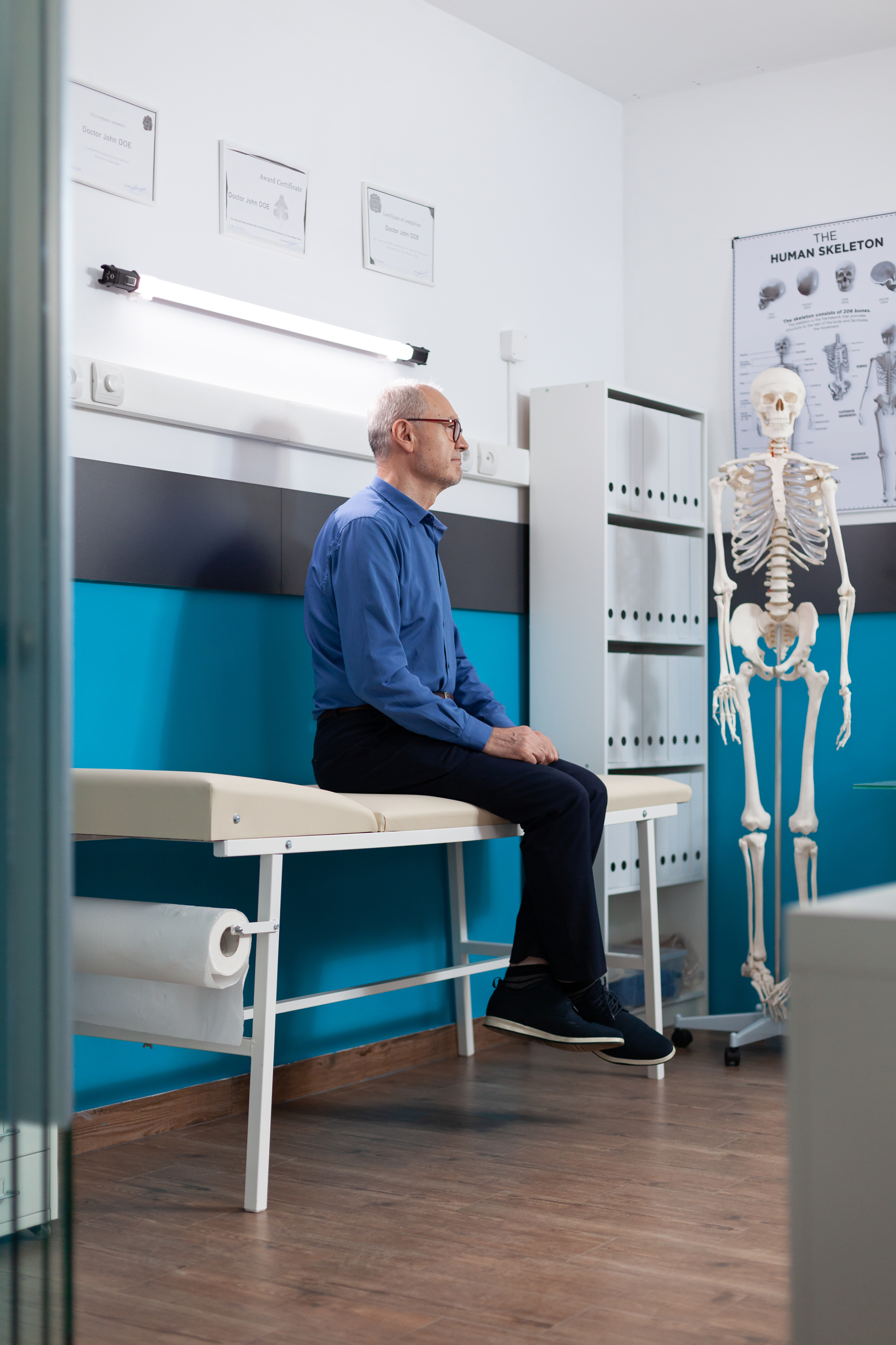 Älterer Patient sitzt ruhig im Untersuchungsraum und wartet auf das Gespräch